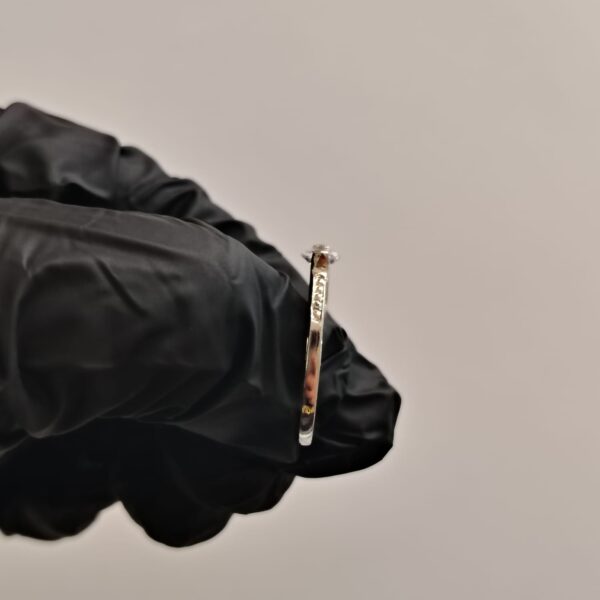 Anillo de plata con piedra preciosa grande y piedras pequeñas incrustadas con detalle de corazones